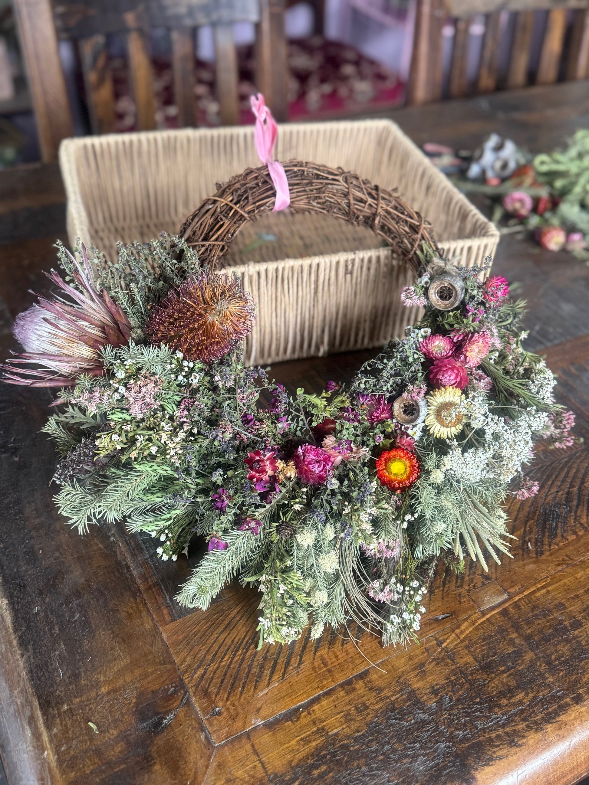 Decorative floral wreaths on a wooden table with a box in the background.