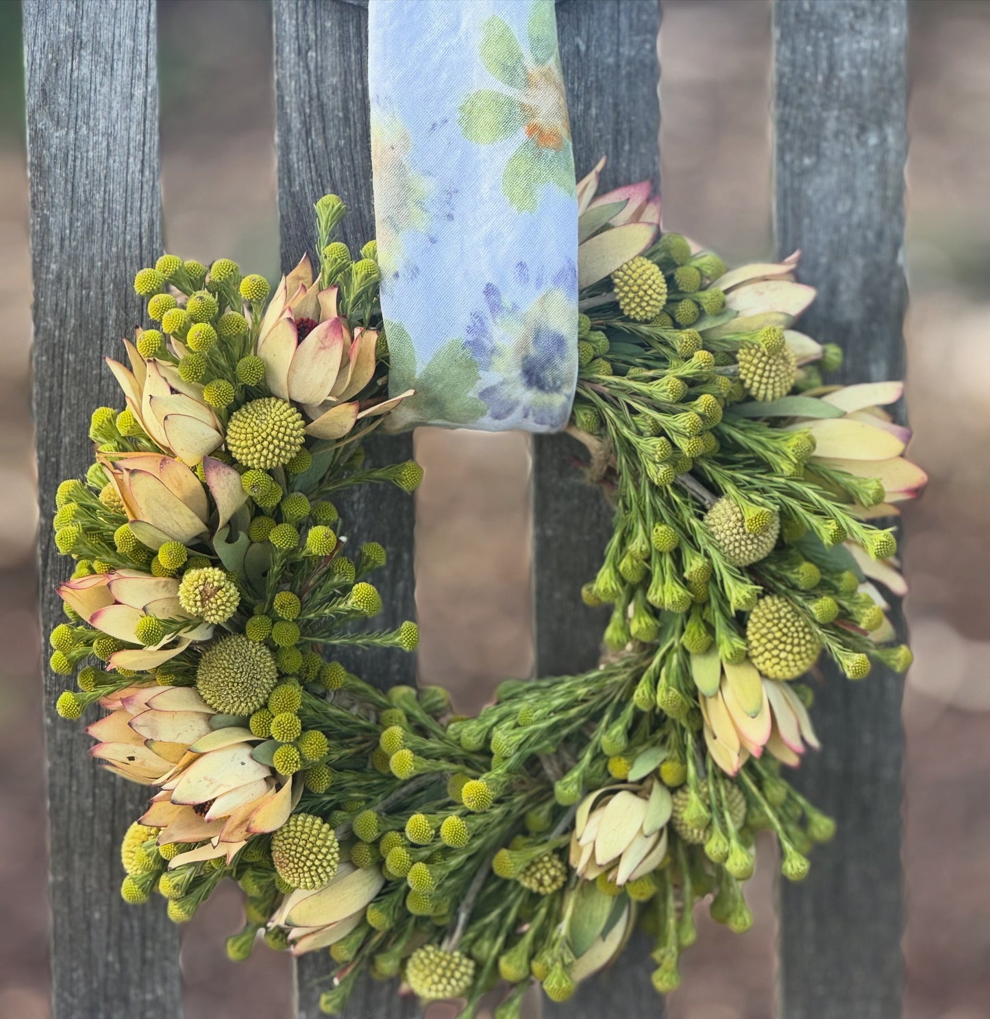 Floral wreath with greenery and flowers on a wooden surface